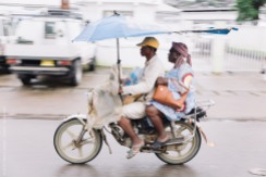 Some local Cameroonians drive by in a motorcycle in front of the HOPE Center.